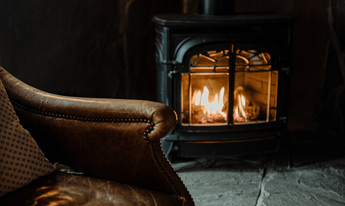 a burning woodstove with a leather chair in front of it at the Wentworth