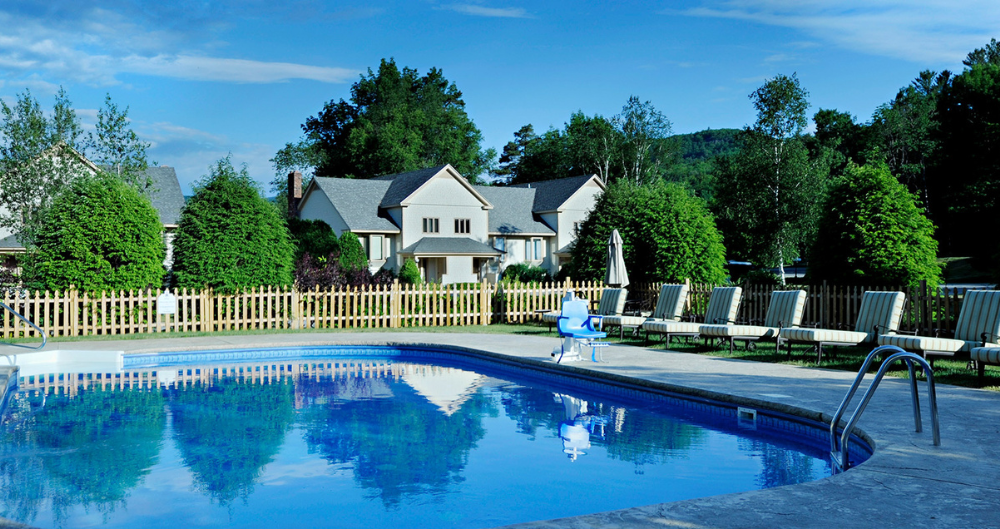 An outdoor pool with chairs and houses in the background at the Wentworth.