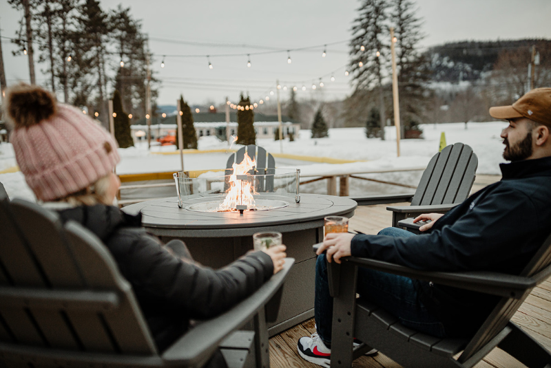 Couple gathered around a a table with an outdoor fire pit.