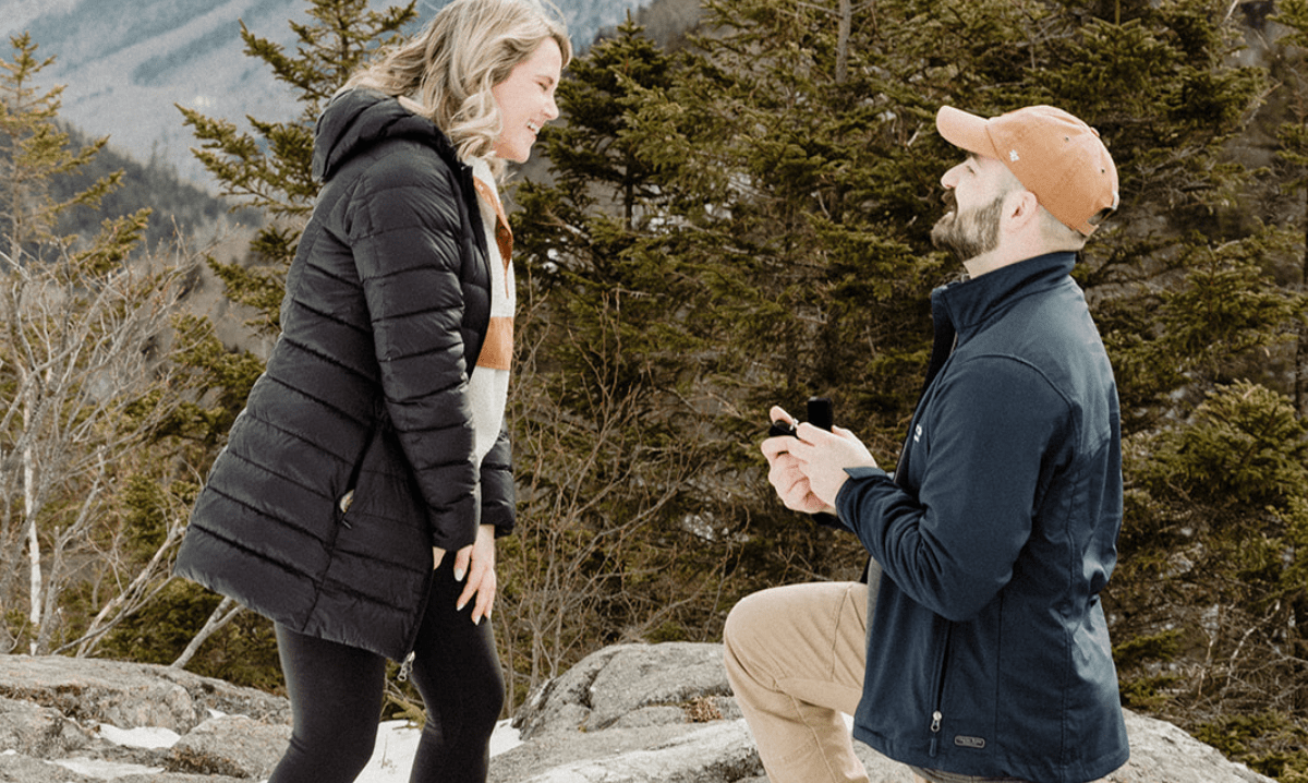 A man proposes to a woman on a mountain top near the Wentworth