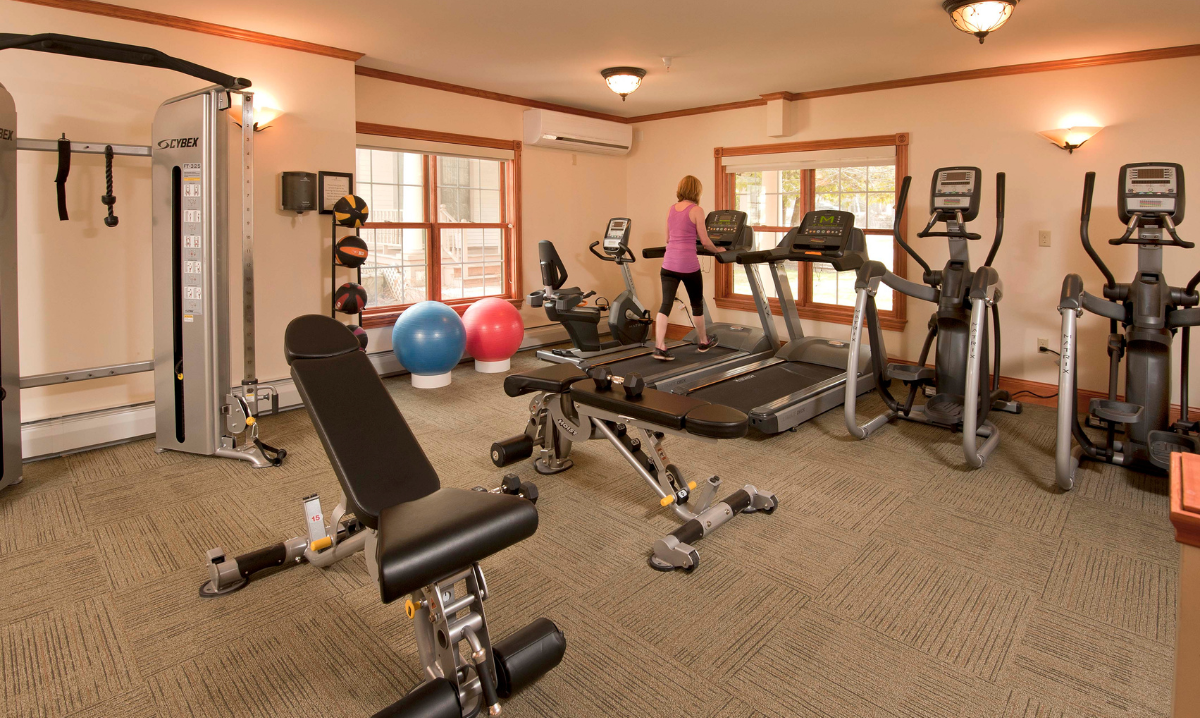 A workout room with equipment and a woman on a treadmill at the Wentworth Inn.