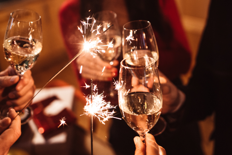 Four hands holding champagne glasses and two sparklers at the Wentworth Inn.
