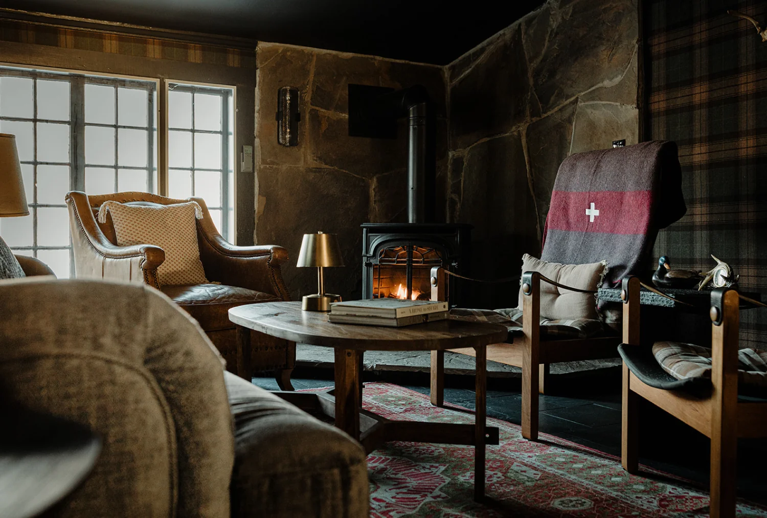 A room at the Wentworth with brown furniture, and a burning wood stove.