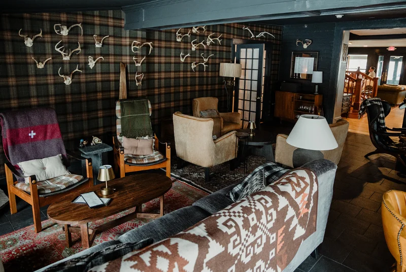 A room with a couch, chairs, and antlers on the wall at the Wentworth