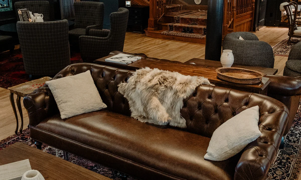 Brown couch with fur blanket, white pillows, and a coffee table.
