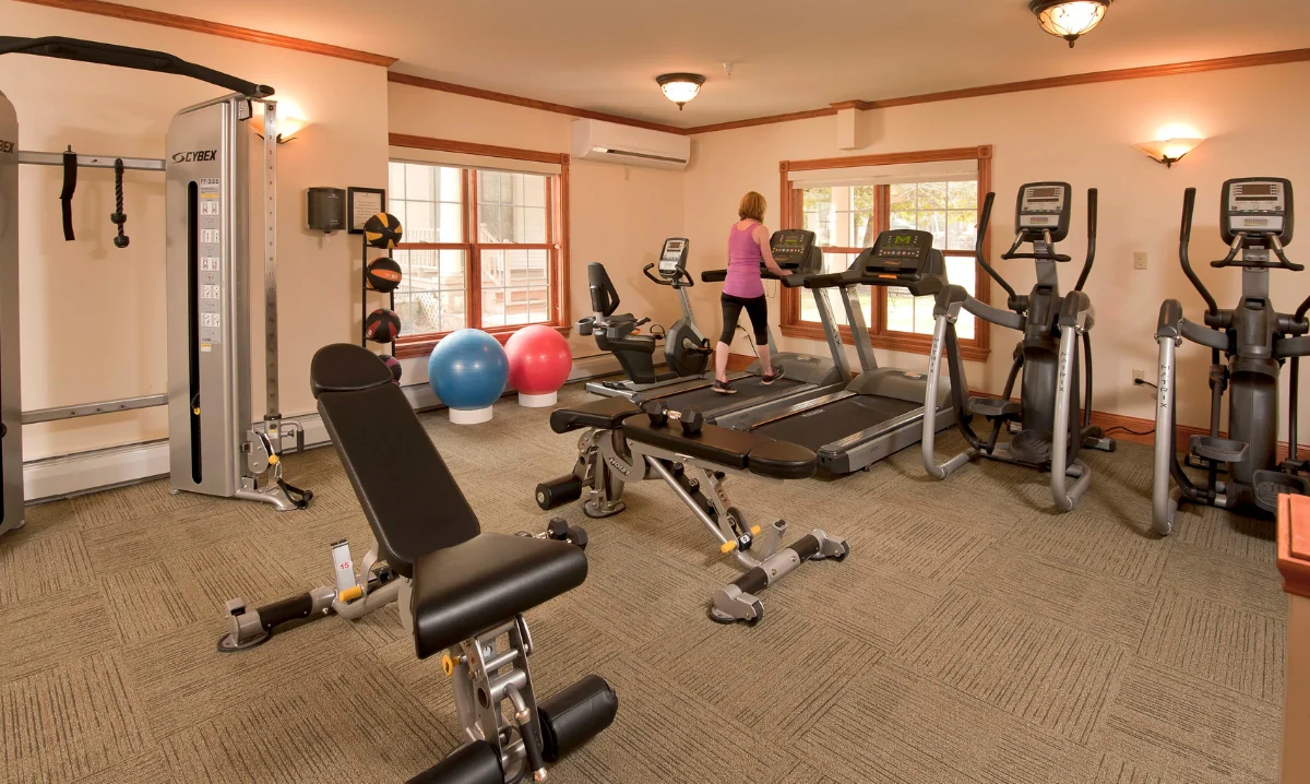 A workout room with equipment and a woman on a treadmill at the Wentworth Inn.