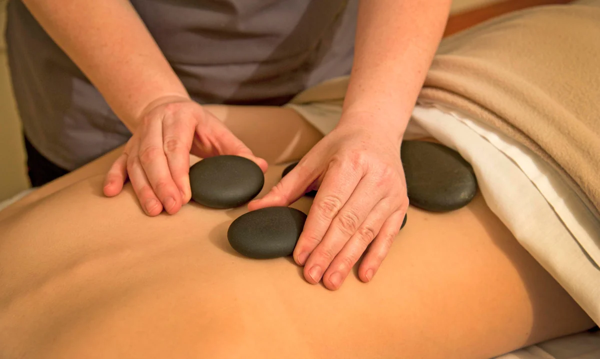 A masseuse placing massage stones on a patients back at the Wentworth Inn.