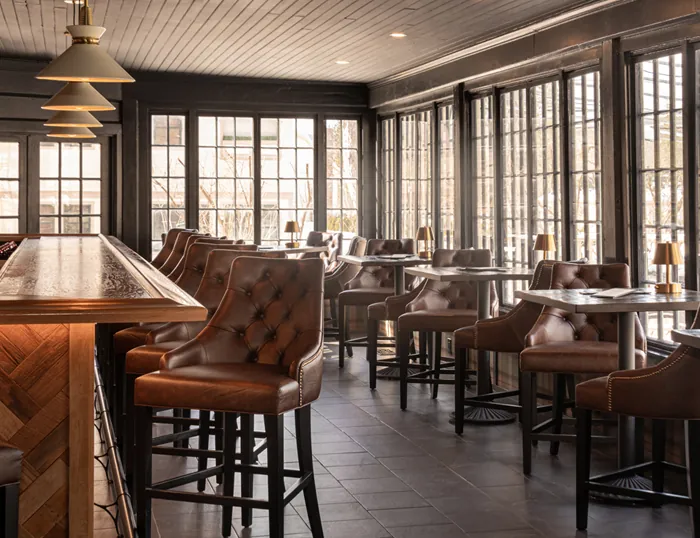 a bar with brown leather chairs at tables at the Wentworth.
